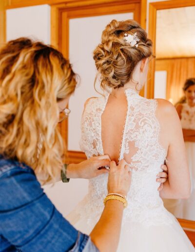Karina Aigner hilft der Braut beim Ankleiden. Rückenteil des Brautkleides ist aus Spitze. Foto: Michelle Peloza