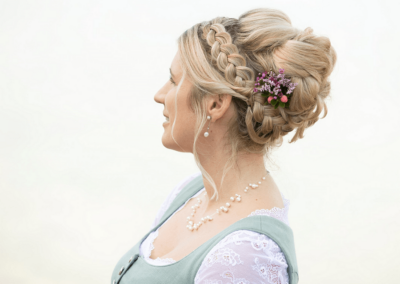 Hochsteckfrisur für Braut, ländlicher Zopf und Blumenschmuck im Haar