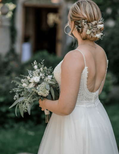 Romantische Steckfrisur, locker im Nacken gesteckt, Blumenschmuck im Haar passend zum Brautstrauß
