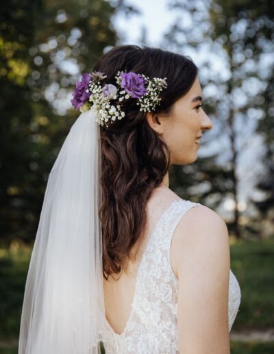 Lange Haare Hochzeitsfrisur, schwarze Haare Bild seitlich, romantische Wellen und Blumenschmuck im Haar